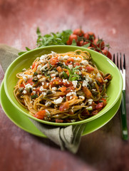 spaghetti with tomatoes cheese capers and arugula, selective foc