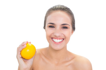 Happy young brunette woman holding an orange