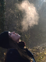 Beautiful girl breathing warm air during a cold autumn morning