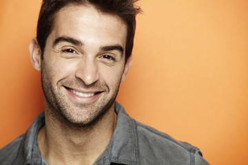 Obraz premium Portrait of mid adult man smiling against orange background