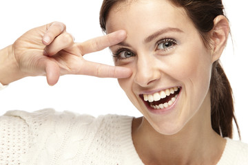 Portrait of a woman making the peace sign on a white background