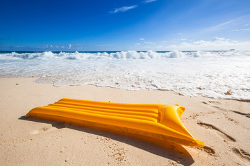 yellow air mattress before the waves