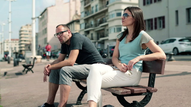Conflicted young couple sitting on bench in the city