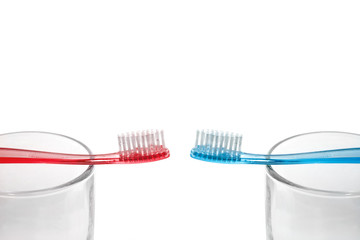 Red and blue toothbrushes are on transparent glasses