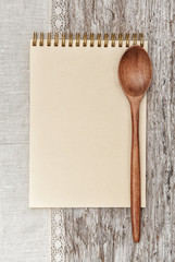 Paper notebook, wooden spoon and linen fabric on the old wood