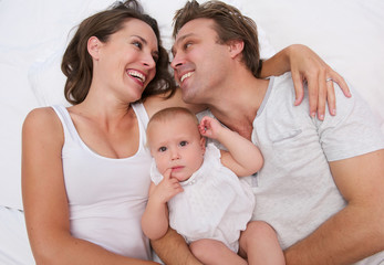 Fototapeta na wymiar Portrait of a loving family holding cute baby in bed