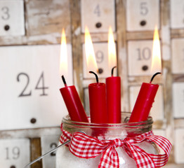 Vier rote brennende Adventskerzen mit Adventskalender