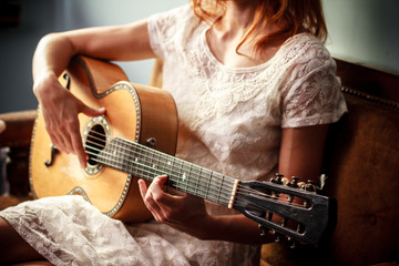 Young woman playing guitar indoors on sunny day