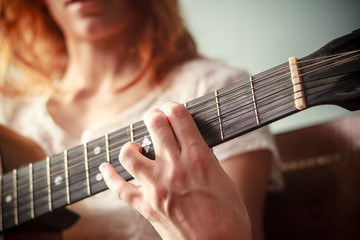 Fototapeta premium Close up on young woman playing guitar