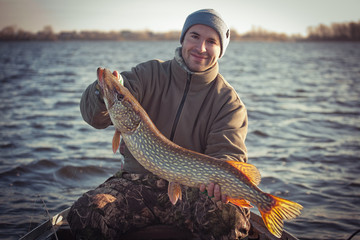 Happy angler with pike fishing trophy