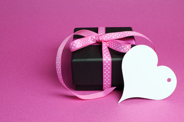 Obraz na płótnie Canvas Elegant black gift with pink ribbon and Heart tag.