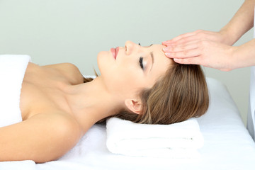 Fototapeta na wymiar Beautiful young woman during facial massage in cosmetic salon