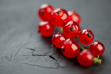 Branch of ripe red currant over black wooden background