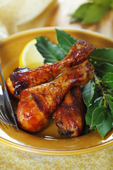 Roast chicken legs with lemon and herbs on plate.