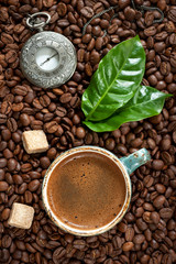 Antique clock and a cup of coffee with coffee beans