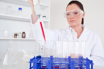 Pretty female biologist holding a manual pipette with sample fro