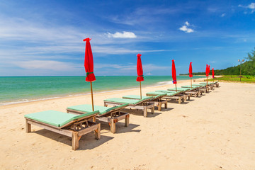 Tropical beach scenery with parasol and deck chairs in Thailand