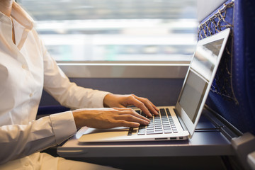 Close-up woman hands typing on a laptop keyboard in the train
