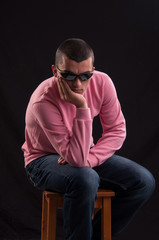 young caucasian man with sunglasses sitting on chair