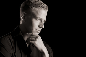 Black and white portrait of young likable man, low key.