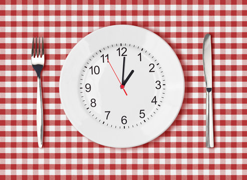 Knife, white plate with clock face and fork on red picnic table
