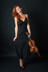 Young woman with violin against black background. Full body port