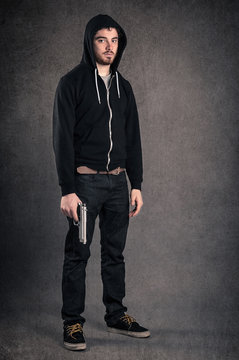 Young man with gun portrait over dark grunge background. Full bo
