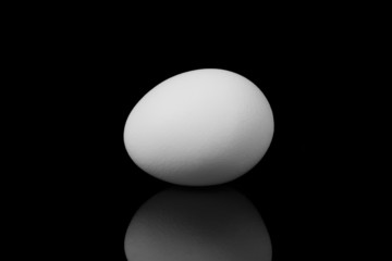 white egg with reflection on black background