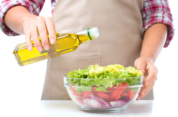 Cook is pouring olive oil into salad
