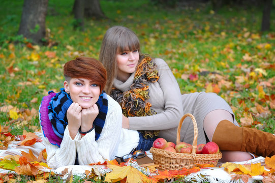 Young girls in the autumn park sitting on the grass