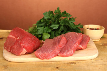 Raw beef meat with spices on wooden table on brown background
