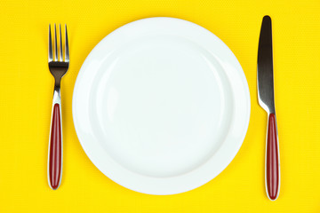 Knife, color plate and fork, on color background