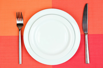 Knife, color plate and fork, on color background