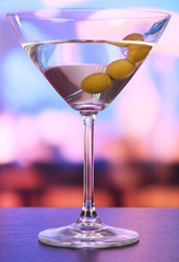 Martini with green olives on table in bar