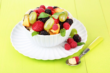 Fruit salad in bowl, on wooden background