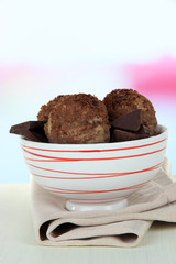 Tasty ice cream scoops in bowl, on wooden table