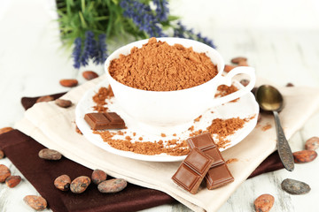 Cocoa powder in cup on napkin on wooden table