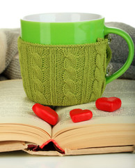 Cup with knitted thing on it and open book close up