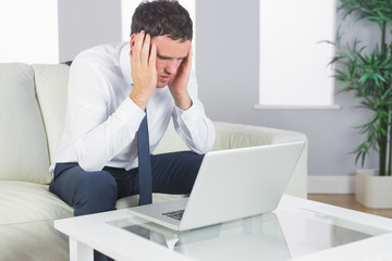 Upset handsome businessman working at laptop