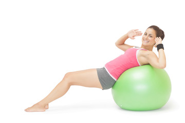 Fototapeta na wymiar Smiling sporty brunette doing sit ups on exercise ball