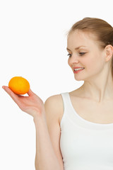 Smiling woman presenting a tangerine while looking at it