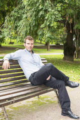 Obraz premium Man sitting and relaxing on a bench in the park.