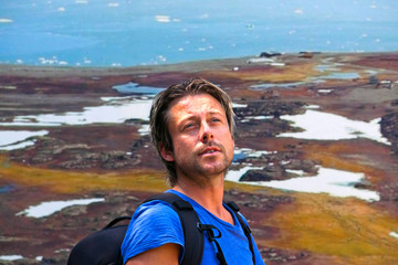 Young man with backpack hiking in toendra landscape. Blonde hair