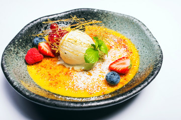 scoop of ice cream on a plate with fresh berries and sweet syrup