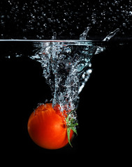 Fresh tomato dropped into water