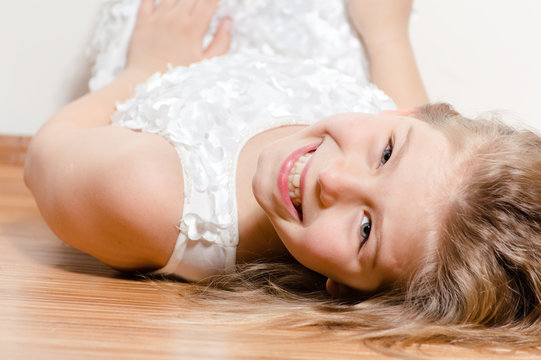 Happy kid lying on floor smiling and looking into camera