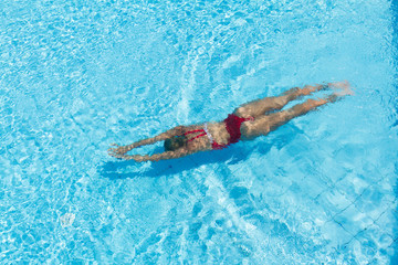 Woman with swimsuit swimming on a blue water pool