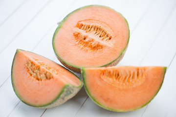 Sliced cantaloupe melon on white wooden boards, close-up