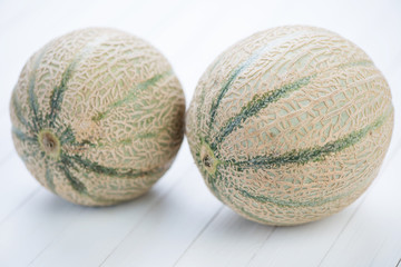 Two ripe cantaloupe melons on white wooden boards, studio shot