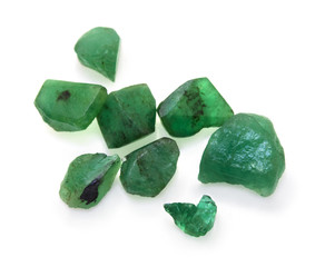 Raw green emerald precious gemstones on the white background.